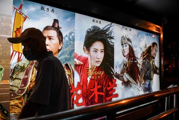 중국 여성을 소재로 한 월트 디즈니의 영화 '뮬란'이 11일 중국에서 개봉했다. 10일 베이징 영화관에서 한 시민이 뮬란 포스터 앞을 지나가고 있다.