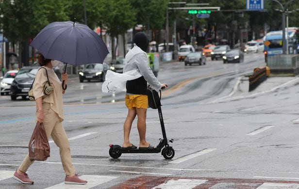 7일 오후 서울 마포구 연남동에서 한 시민이 비를 맞으며 전동 킥보드로 도로를 건너고 있다. 태풍 '하이선' 북상으로 전국에 비가 내린 이날 공유 전동 킥보드 업체 대부분이 정상 운행 서비스를 헸다./장련성 기자
